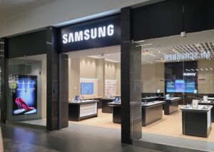 Samsung store in a mall with glass storefront, bright lighting, and product displays on tables inside