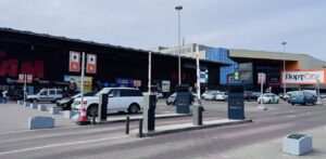 Parking lot in front of a mall labeled PortCity, with several cars and payment kiosks.